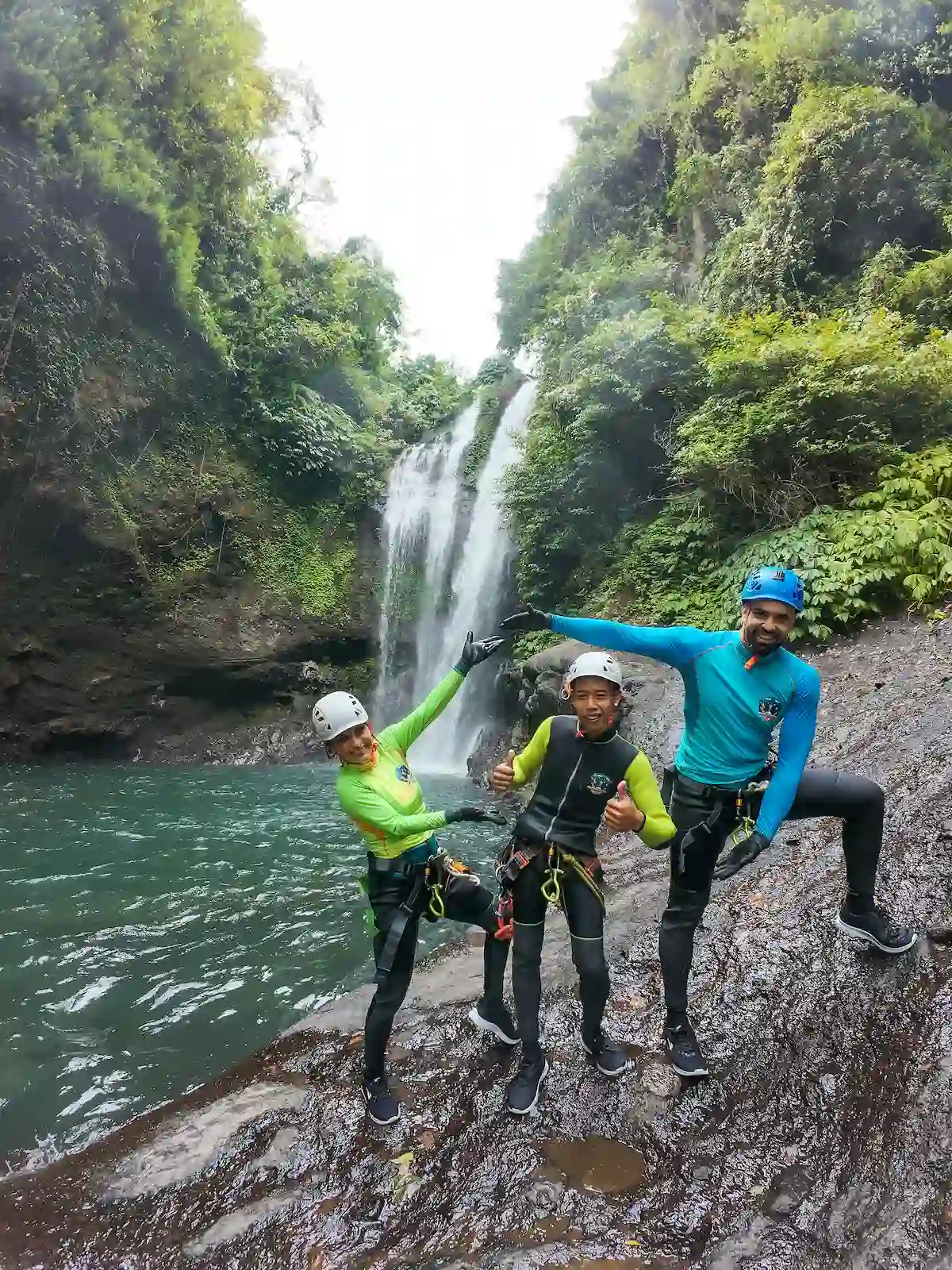 Three canyoners celebrating in front of Aling-Aling Waterfall at the finish