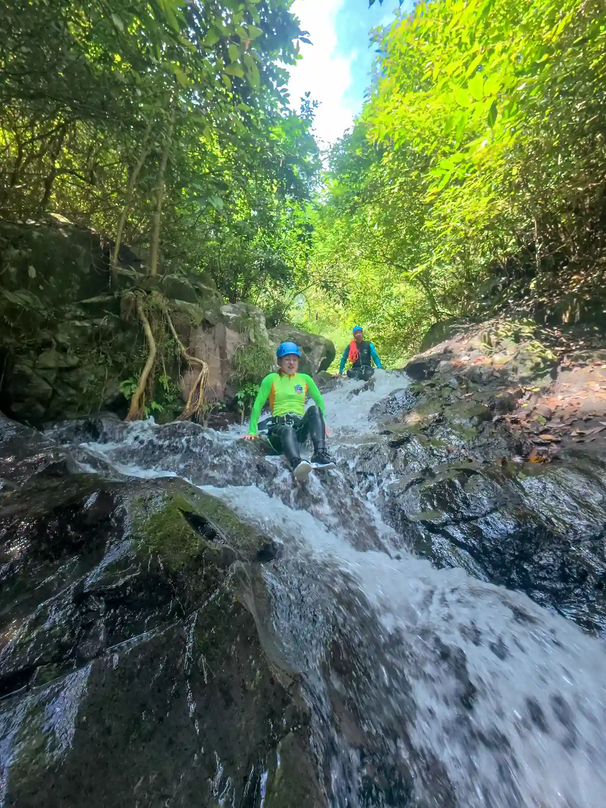Guest riding a natural rock slide with a guide close behind