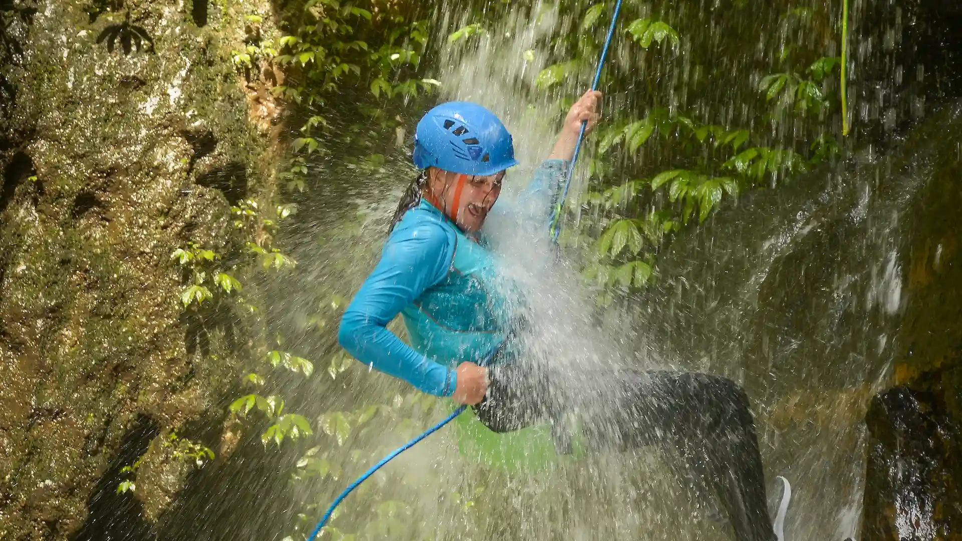 Guest rappelling through waterfall spray on the Splash Canyon taster in North Bali