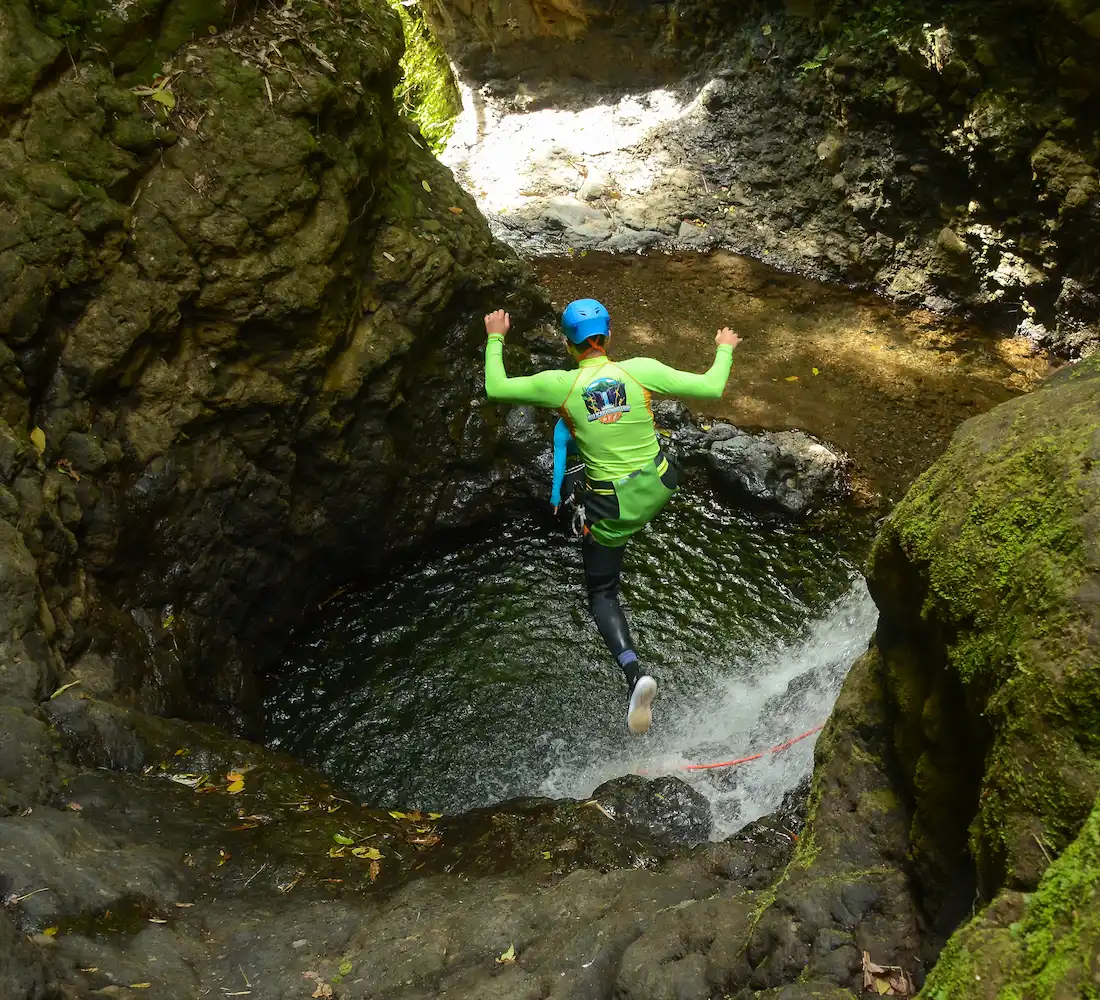 A canyoner taking an optional jump into a deep pool in Bali